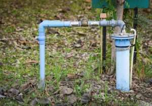 Private well water system with blue PVC piping and a sediment filter housing, illustrating standard rural well setups that may require iron removal or water filtration solutions.