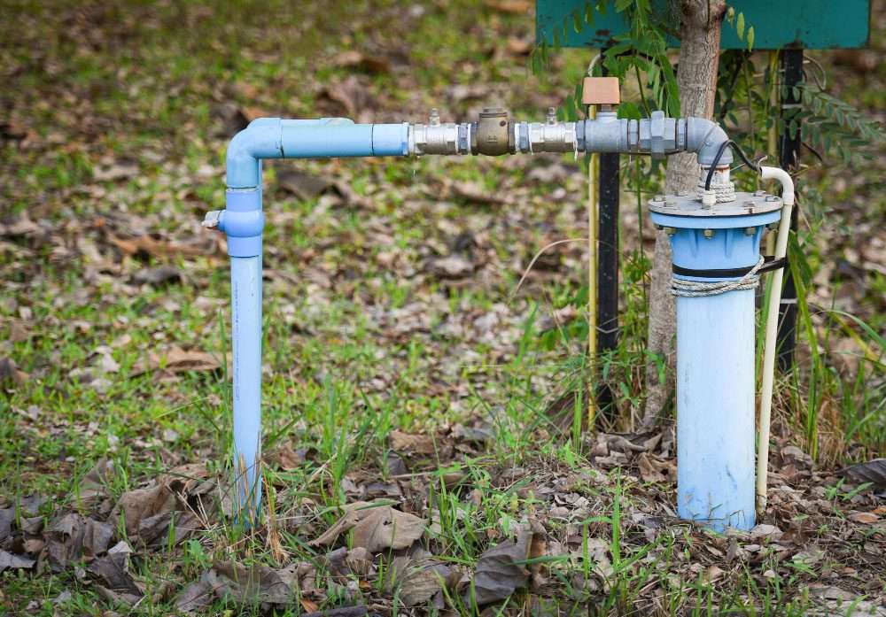 Private well water system with blue PVC piping and a sediment filter housing, illustrating standard rural well setups that may require iron removal or water filtration solutions.