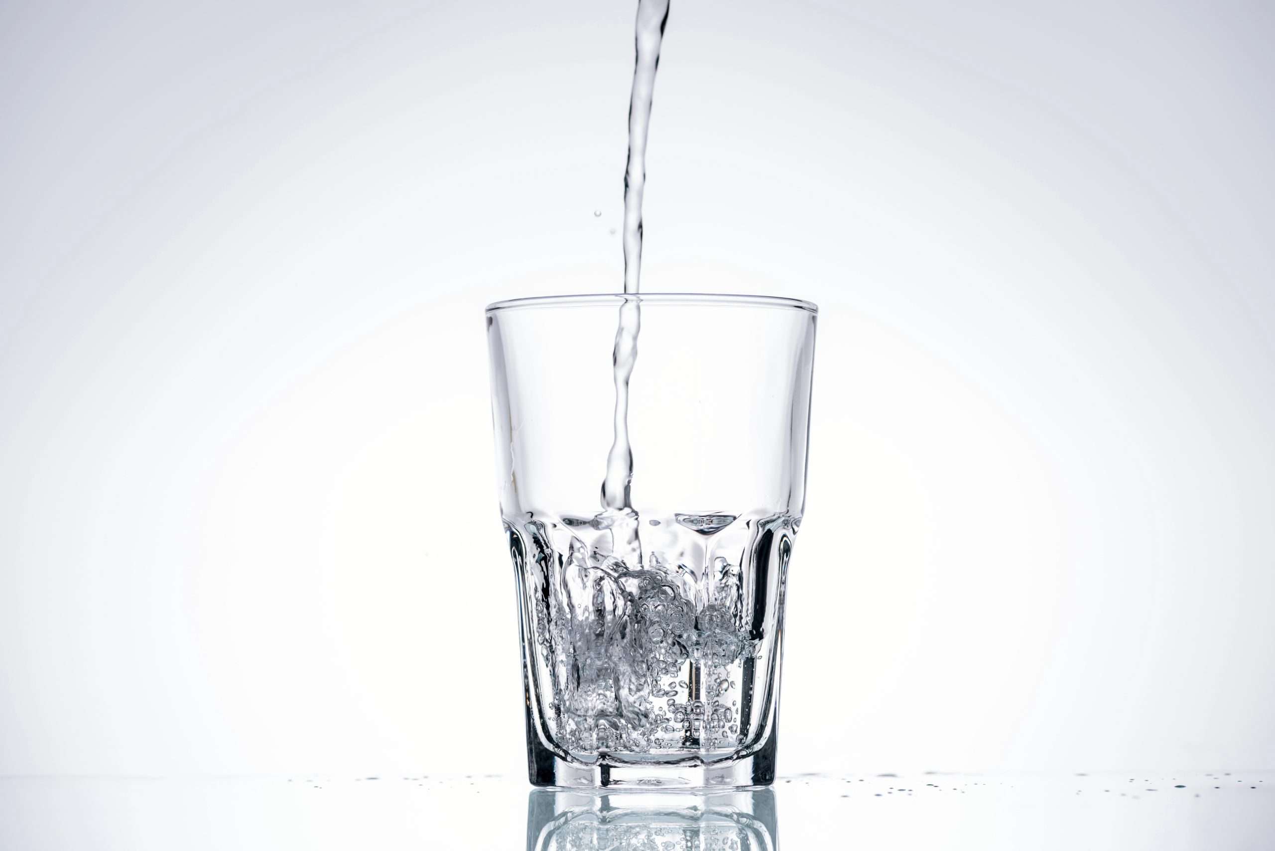 Water pouring into a clear glass on a white backdrop